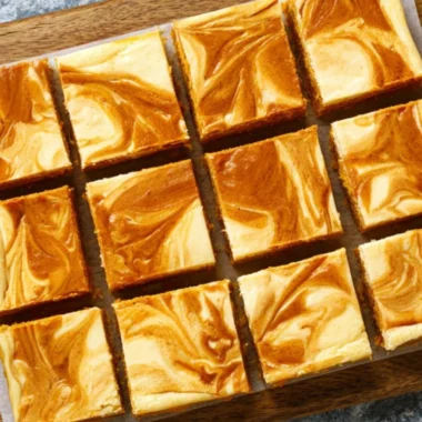 Swirled pumpkin cheesecake bars with a creamy texture and pumpkin topping.