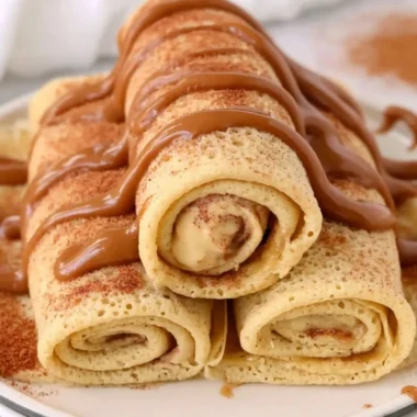 Cinnamon roll protein crepes with a drizzle of icing and cinnamon.